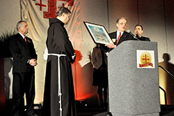 Mike LeCuyer, second from right, regional chairman of the Franciscan Foundation for the Holy Land and a member of St. John Vianney Parish in Fishers, Ind., in the Lafayette Diocese, presents a gift to Franciscan Father Peter Vasko at the J.W. Mariott hotel in Indianapolis during a March 22 foundation fundraising dinner, which in part celebrated the 20th anniversary of the establishment of the foundation. Looking on are dinner organizers Mike Hirsch, left, and Richard Sontag, right, both members of St. Luke the Evangelist Parish in Indianapolis. (Photo by Sean Gallagher)