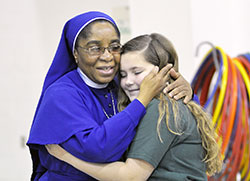 Daughters of Mary Mother of Mercy Sister Loretto Emenogu receives a hug from Christ the King School fifth-grader Madelyn Reinhardt on March 20. Madelyn and the students of the Indianapolis school helped raise $13,000 for the Missionary Childhood Association, which Sister Loretto promotes. (Photo by Natalie Hoefer)