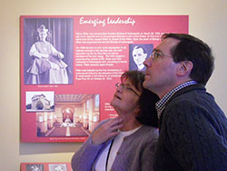 Mary Ritter and Paul Scales study a display in a museum room now located in the restored birthplace and boyhood home of Cardinal Joseph E. Ritter in New Albany on March 13. They traveled from Cincinnati to hear Louisville Archbishop Joseph Kurtz and see the restoration of Mary Ritter’s great-uncle’s New Albany childhood home. A portrait of Cardinal Ritter graces the wall behind them. (Photo by Patricia Happel Cornwell)