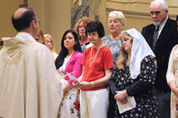 Verneta Marchant, center in the red shirt, listens as Conventual Franciscan Father Mark Weaver, pastor of St. Joseph University Parish in Terre Haute, addresses her and her fellow catechumens and candidates during the parish’s Easter Vigil Mass on April 19. (Submitted photo)