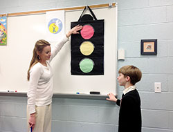 As part of the archdiocese’s Circle of Grace program, Amy Shields uses a stoplight to explain to children how they should approach safe and unsafe touching. For example, if a parent hugs a child, that’s a green light situation (it’s OK for the child to hug back because the child is comfortable with the person.) If a friend at school hugs a child, it may be a yellow light situation (if the child is comfortable, then the hug is fine. If the child doesn’t want a hug, it’s not.) If a stranger were to hug a child, it would be a red light situation where the child would need to tell a trusted adult. A kindergarten catechism teacher at St. Paul Parish in Tell City, Shields explains the concept to her son, Griffin. (Submitted photo)