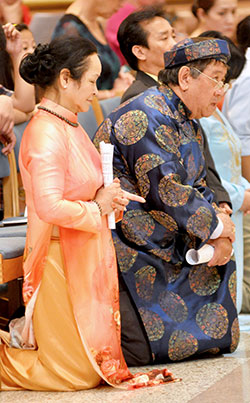 Hoa Truong and her husband, Toan Tran, members of the Vietnamese Catholic Community at St. Joseph Parish in Indianapolis, kneel during the Asian and Pacific Islander Mass at SS. Peter and Paul Cathedral in Indianapolis on April 12. They are wearing traditional Vietnamese native garb, called ao dai, for the special Mass. (Photo by Natalie Hoefer)