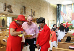 Brenda Hall, left, a member of Holy Angels Parish in Indianapolis, shares some of her poetry with fellow parishioners Jerry Monette and Anne Scott Murrell. Hall recited one of her poems during the Connected in the Spirit Pentecost Mass held on May 24 at St. Rita Church in Indianapolis. “We must let the Holy Spirit set us free,” one verse begins. “Let the Holy Spirit be what it be.” (Photo by Victoria Arthur)