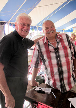 Bill Kidwell, right, is usually all smiles when it’s time for the St. Jude Parish Festival in Indianapolis. This year’s festival on June 23-25 will mark his 26th year of chairing the festival. Here, he poses for a photo at the 2012 festival with Father James Wilmoth, the pastor of St. Roch Parish in Indianapolis. (Submitted photo)