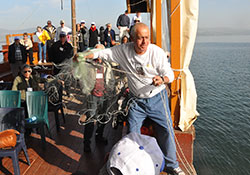 In a boat on the Sea of Galilee, a man demonstrates how the disciples would have fished in this photo from Feb. 7, 2015. Those embarking on the Holy Land pilgrimage with Msgr. William F. Stumpf on Jan. 23 to Feb. 2, 2017, will enjoy a similar experience. (File photos by Natalie Hoefer)