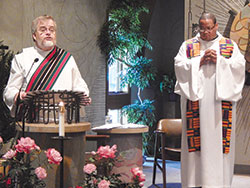 Deacon Kerry Blandford, parish life coordinator of St. Andrew the Apostle Parish in Indianapolis, left, proclaims the Gospel during a Sept. 9 prayer service in the parish’s church. Also pictured is Father Douglas Hunter, associate pastor of St. Pius X Parish and chaplain coordinator at Bishop Chatard High School, both in Indianapolis. (Photo by Mike Krokos)