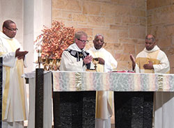 Father Michael Hoyt, second from left, pastor of St. Michael the Archangel Parish in Indianapolis, prays the eucharistic prayer during the archdiocesan St. Martin de Porres Mass celebrated on Nov. 3 at his parish’s church. Also pictured are Father Douglas Hunter, left, Father Kenneth Taylor and Society of the Divine Word Father Charles Smith. (Photo by Mike Krokos) 