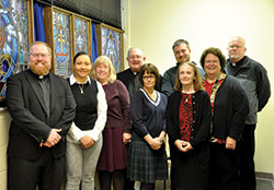 Father Joseph Newton, left, archdiocesan vicar judicial, poses on Nov. 29, 2016, with fellow staff members in the archdiocesan metropolitan tribunal. They are, from left, Swiden Torres-Torrijos, Ann Tully, Msgr. Frederick Easton (retired vicar judicial and now adjunct vicar judicial), Nancy Thompson, Joseph Gehret, Kay Summers, Peggy Crawford and Benedictine Father Patrick Cooney. The staff posed in the St. Alphonsus Liguori Chapel in the Archbishop Edward T. O’Meara Catholic Center in Indianapolis. Not pictured is Daniel Ross, a recent addition to the tribunal staff. (Photo by Natalie Hoefer)