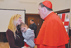 Young widow Jennifer Trapuzzano, 28, and her daughter Cecelia bid farewell to Cardinal Joseph W. Tobin on Dec. 5, 2016. She had turned to him earlier that fall about an idea she had for a Catholic widow’s retreat, which has come to fruition and will be held at the Benedict Inn Retreat & Conference Center in Beech Grove on Sept. 22-24. (File photo by Natalie Hoefer)