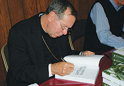 On Nov. 20, 2006, Archbishop Daniel M. Buechlein signs a copy of Still Seeking the Face of the Lord, his second collection of the columns he wrote for The Criterion during his 19 years as the spiritual leader of the Church in central and southern Indiana. (File photo by Mary Ann Garber)