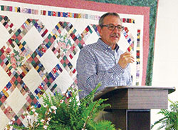 Paul Pavey of St. Vincent de Paul Parish in Shelby County speaks after accepting a check for $8,044.80 from a tea party and quilt raffle that has jumpstarted a new St. Vincent de Paul Society to help the poor in Shelby County. He stands in front of the quilt that was donated to help raise money for the society. (Submitted photo)