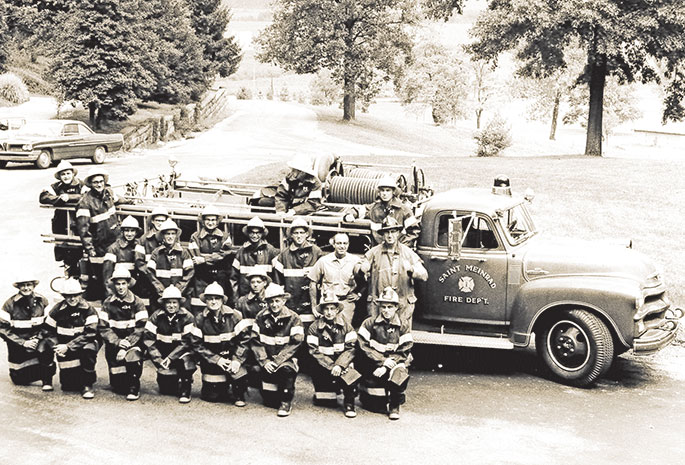 Volunteer firefighters from St. Meinrad, including several Benedictine monks, pose with their truck in this photo which originally appeared in The Criterion on Oct. 14, 1966. At that time, the fire department included two companies, one to serve the town of St. Meinrad, and the other to serve Saint Meinrad Archabbey. Second from the right in the first row is Hubert Werne, captain of the town company, and on the far right in the first row is Benedictine Brother Daniel Linskens, captain of the abbey company. On the far right in the second row is Benedictine Father Kevin Ryan, who was rector of the former Saint Meinrad Seminary High School and served as fire marshal. The volunteer fire department continues to be headquartered today at the eastern foot of the hill on which Saint Meinrad Archabbey and the seminary it operates is located. Benedictine Brother Benjamin Brown, who joined the fire department in 1972, is the only monk firefighter at this time. 