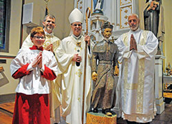 Altar server John Crawley, left, Father Jonathan Meyer, Archbishop Charles C. Thompson and Deacon Robert Decker pose on Nov. 6 in St. Paul Church in New Alsace, a campus of All Saints Parish in Dearborn County, after a Mass in which Archbishop Thompson blessed a statue of the Servant of God Bishop Simon Bruté. Deacon Decker carved the statue. John built a shrine for the statue in the church, which was dedicated by Bishop Bruté in 1838, for an Eagle Scout project. (Photo by Sean Gallagher)