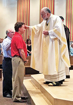 Father James Farrell, pastor of St. Pius X Parish in Indianapolis, confers the sacrament of confirmation upon Ward Walker during Mass on May 25.  (Submitted photo)