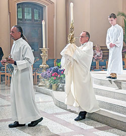 Archbishop Charles C. Thompson carries a monstrance holding the Blessed Sacrament during a eucharistic procession on June 12 at SS. Peter and Paul Cathedral in Indianapolis on the Solemnity of the Most Holy Body and Blood of Christ, traditionally known as Corpus Christi. Assisting in the procession are Frank Lloyd, left, and Thomas Motyka. Parishes across central and southern Indiana celebrated Corpus Christi last weekend. More photos from the feast day honoring Christ’s presence in the Eucharist can be found on page 16. (Submitted photo)