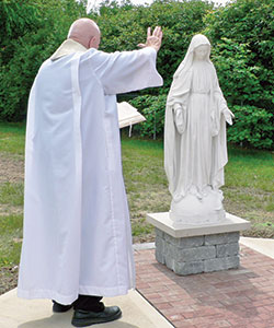In this photo from May 28, Father John Hall, pastor of St. Anne Parish in New Castle, blesses a Marian statue from the former St. Rose of Lima Parish in Knightstown that now graces the St. Anne parish cemetery. (Submitted photo)