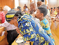 Aurore Gbetie, a member of St. Christopher Parish in Indianapolis and a native of the African country of Benin, bows in prayer after receiving the Eucharist during a Mass celebrating Africa Day (or Africa Freedom Day) at St. Rita Church in Indianapolis on June 4. (Photo by Natalie Hoefer)