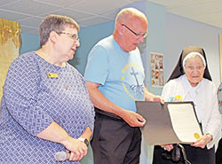 Benedictine Sister Mary Carol Messmer, right, receives a certificate on June 4 from Dennis Buckley, mayor of Beech Grove, declaring June 12 as “Sister Mary Carol Day” in the city. Benedictine Sister Julie Sewell, prioress of the monastery, looks on at left. (Submitted photos by Jennifer Lindberg)