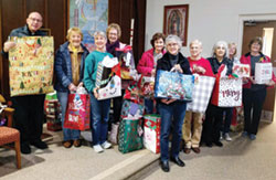 Father Stephen Giannini, pastor of St. Martin of Tours Parish in Martinsville, left, joins members of the parish’s Altar Society as they pose for a photo with their Christmas gifts for local nursing home residents and families from the Martinsville community.  (Submitted photo)