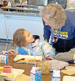 Mila Baker, left, a pre-kindergarten student at St. Roch School in Indianapolis, smiles during a lunch period at Lori Tobin, a member of St. Roch Parish who volunteers in the school’s cafeteria. (Submitted photo)