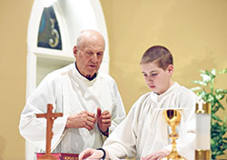 Carl Bohman, left, gives directions to altar server Andrew Ruf during a Jan. 24 Mass at St. Peter Church in Franklin County. Bohman trains young altar servers in the Batesville Deanery faith community in part by serving at Mass alongside them. (Photo by Sean Gallagher)
