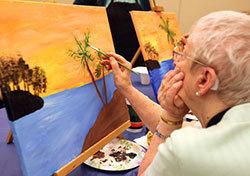 Joyce Elliott, of Crown Point, fills in a palm tree on the tropical island she painted at the National Cancer Survivors Day Canvas Painting Party she attended June 5 at Marian Education Center. (Marlene A. Zloza photo)