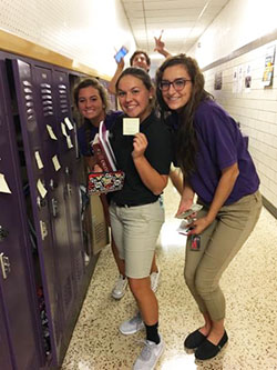 Maddy Halter, left, Hannah Greenwood, and Meg Herman place post-its on student lockers, unaware of photobomber Thomas Vieke. Submitted photo.