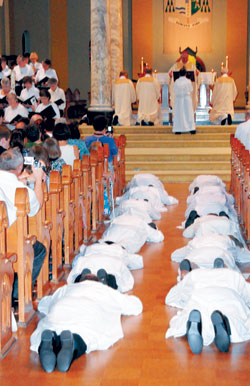 The candidates for diaconate lie prostrate on the floor of the main aisle while the choir and the congregation sing the Litany of Saints. This act is intended as a sign of total submission to God, unworthiness for the office, and complete dependence on God and the prayer of the Mystical Body of Christ. (Message photo by Paul R. Leingang)