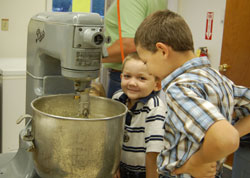 Sam and Lane Barnard watch the dough mix as they help make doughnuts on a recent Sunday morning.