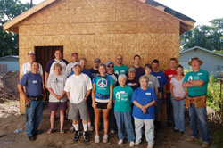 Matthew 25 volunteers from St. Matthew Cathedral in South Bend stand before a home in progress for Habitat for Humanity.