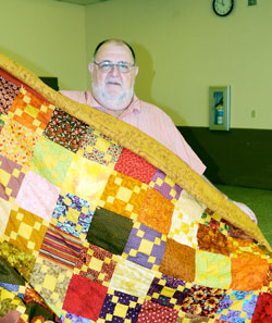Steve Barron, a volunteer mentor for several participants in the PLUS program at the Wabash Valley Correctional Facility in Carlisle, shows off the quilt made for him by one of the men. Quilts have been given for the homeless, to families of soldiers killed in action and to non-profit organizations. (Message photo by Paul R. Leingang)
