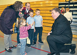 Archbishop Joseph W. Tobin reacts to 3-year-old Kathryn Mack showing him her age during a Feb. 19, 2013, reception at St. Louis Parish in Batesville following a Mass celebrated there by the archbishop for Catholics in the Batesville Deanery. Joining Kathryn in meeting the archbishop are members of her family, from left: Deb, Grace (partially obscured), Pete, Christian and Spencer Mack, all members of St. Louis Parish. (File photos by Sean Gallagher) 