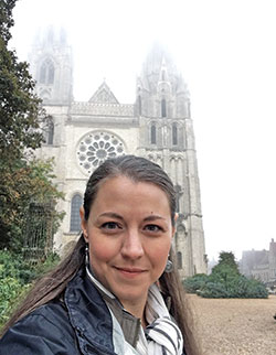 Jennifer Brandon poses in front of fog-enshrouded Chartres Cathedral in France. The music teacher at St. Matthew the Apostle School in Indianapolis visited the cathedral as part of her travels for a book she is co-authoring, Places of Light: The Gift of Cathedrals to the World. (Submitted photo)