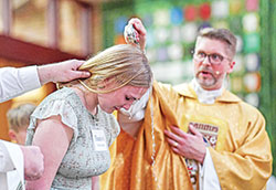 Father Sean Danda baptizes Emma Gamble during the Easter Vigil Mass at St. Malachy Church in Brownsburg on April 8. (Submitted photo by Michael Harker)