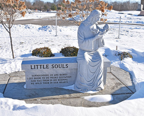 Within the cemetery of St. Mary Parish in Greensburg on Jan. 20, a statue of Jesus smiling and holding a baby marks the site of a section for burying miscarried babies called Little Souls Cemetery, a concept of Covenant Resources Miscarriage Ministry founded by Rebecca and Chris Harpring of St. Mary Parish. The couple’s son Louis served as the model for the baby in the image, created by Michael McCarthy of St. John the Evangelist Parish in Indianapolis exclusively for the Harpring’s use. (Photo by Natalie Hoefer)