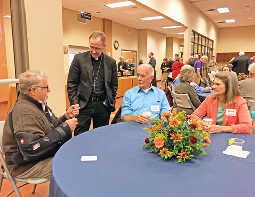 Archbishop Charles C. Thompson speaks with Jim Evrard of St. Mary Parish in Lanesville, left, and Dan and Melissa Coffey of Holy Family Parish in New Albany during an archdiocesan United Catholic Appeal event at St. Mary-of-the-Knobs Parish in Floyd County on Oct. 30. (Photo by Leslie Lynch)