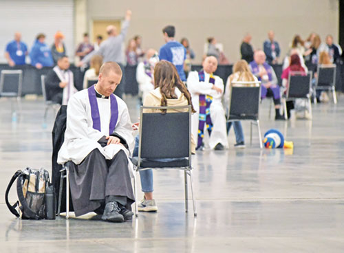 Father Kyle Rodden, left, is one of dozens of priests hearing confessions on Nov. 21 in an exhibit hall at the Indiana Convention Center in Indianapolis used for the sacrament of penance during the National Catholic Youth Conference. The priest is pastor of St. Joseph Parish in Corydon and St. Mary Parish in Lanesville. (Photo by Sean Gallagher)