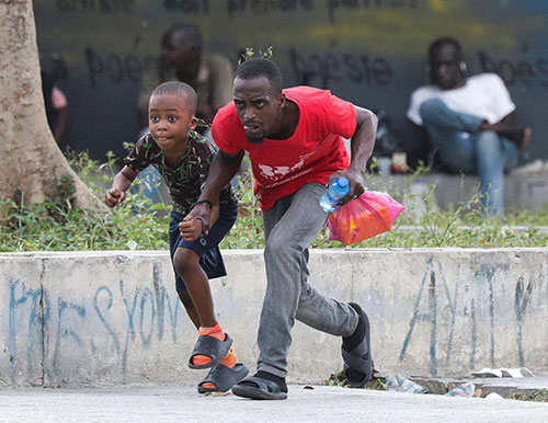 A man and child take cover from gunfire near the National Palace in Port-au-Prince, Haiti, March 21, 2024. (OSV New photo/Ralph Tedy Erol, Reuters)
