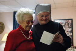 Sister Margaret Banar, a member of the international Little Sisters of the Poor order, looks at photographs with St. Augustine Home for the Aged resident Beatrice Spurgeon of Indianapolis. Sister Margaret said her habit “opens doors” that otherwise would not be accessible in her ministry. (Photo by Mary Ann Wyand) 