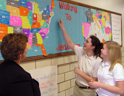 At Holy Spirit School in Indianapolis, sixth-grade student Rachel Clark, middle, tracks the progress of her team’s path in “Walking to Jerusalem,” a 6,236-mile journey that the school community is making as a Lenten journey. Principal Rita Parsons, left, and seventh-grade student Lindsey Newhart also examine the map. (Photo by John Shaughnessy) 