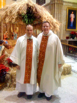 On Christmas Eve in 2008, Deacon Peter Marshall, left, poses for a photograph at St. Mary Church in Indianapolis with Father Michael O’Mara, pastor, near a Nativity scene. Deacon Marshall was a member of St. Mary Parish when he entered the seminary. (Submitted photo) 