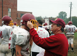 Known for his passion for the game and his loyalty to his players, Scecina head football coach Ott Hurrle talks with one of his players during practice. (Photo by John Shaughnessy)