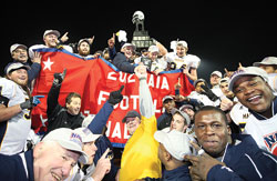 Marian University head coach Ted Karras Jr., top center, shakes hands with associate head coach Martin Mathis as the team celebrates and holds up the NAIA national championship trophy after defeating Morningside College 30-27 at Barron Stadium in Rome, Ga., on Dec. 13. (Photo by Brittany Hannah/Rome News-Tribune)