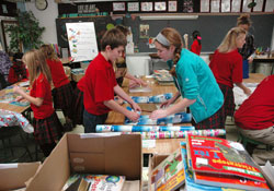 St. Matthew School students David Denise and Maddie Tarowsky, center, team up to wrap books as gifts for children in homeless shelters. The effort stemmed from the Indianapolis school’s seventh-grade class to collect books for the school’s library and to share them with children in need. (Photo by John Shaughnessy)