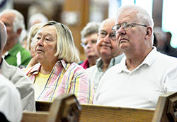 Janet and Gene Stemmle, members of St. Joseph Parish in St. Leon, and Dave Berkemeier, a member of St. Maurice Parish in Decatur County who is seated behind them, listen to Archbishop Joseph W. Tobin speak during the press conference at St. Louis Church in Batesville on June 6. (Photo by Sean Gallagher)
