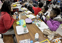 Lauren Graves, left, an eighth-grade student at St. Joan of Arc School in Indianapolis, eats lunch on Jan. 13 with Emily Wright, second from right, and Dorinda Bartone, both first-grade students at the Indianapolis North Deanery School. Graves and other older students at St. Joan of Arc help younger students during their lunch to help them develop leadership skills as a part of “The Leader in Me” program. (Photo by Sean Gallagher)