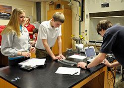 Juniors Meredith Opel, left, Adam Schubach and Kevin Lemmel of Roncalli High School in Indianapolis perform an experiment to measure force using computer-interfaced technology in an honors physics class on Jan. 15. (Photo by Natalie Hoefer)