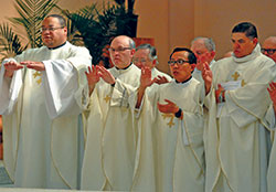 Fathers Douglas Hunter, left, Vincent Lampert, Minh Duong and Juan José Valdés join in the eucharistic prayer during the April 16 chrism Mass. (Photo by Sean Gallagher)