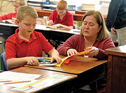 Amy Kersey helps second-grader Jackson Boggs on Jan. 9 at St. Michael School in Brookville. Kersey is the school’s second-grade teacher. (Photo by Sean Gallagher)