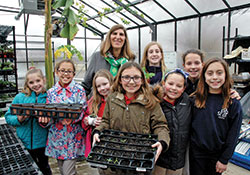 Members of the horticulture club at St. Bartholomew School in Columbus pose for a photo with principal Helen Heckman in the school’s greenhouse-outdoor learning lab in early March. (Photo by John Shaughnessy)